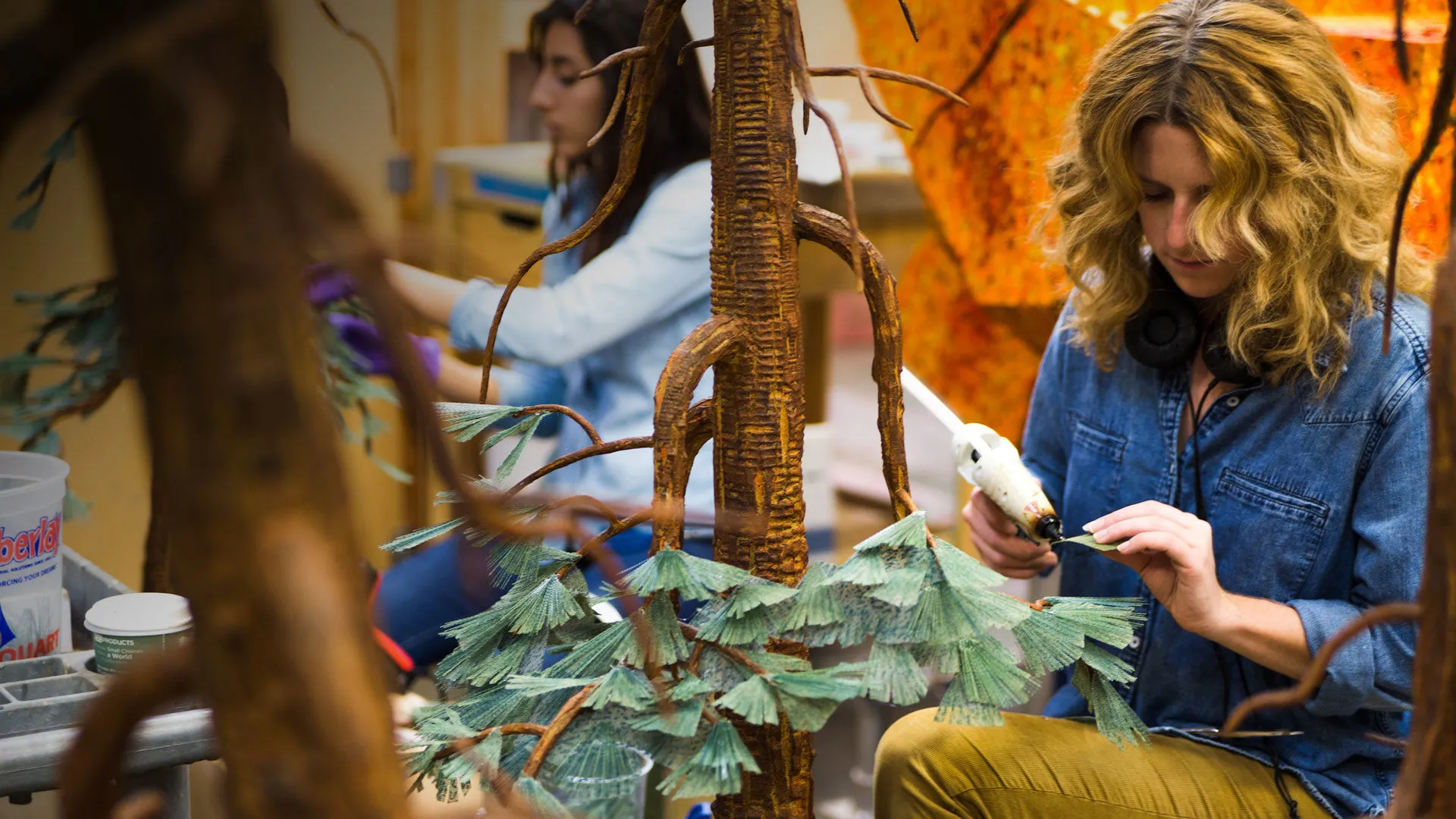 A LAIKA employee glueing handmade leaves onto a tree on the set of oMissing Link